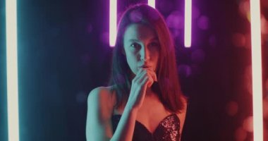 Yavaş çekimde genç bir kadın, güzel neon arka planda kameraya bakıyor. Elektronik sigara ve milenyum konsepti.