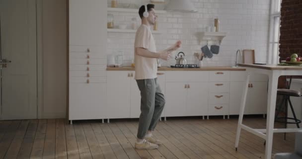 开心的学生在家里跳舞 手里拿着一杯咖啡 戴着耳机 一个人玩得很开心 休闲活动和现代青年概念 — 图库视频影像