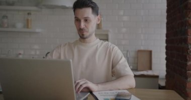 İş adamının portresi, evdeki mutfakta internetten konuşan ve dizüstü bilgisayar kullanan biri. İş iletişimi ve uzak çalışma kavramı.
