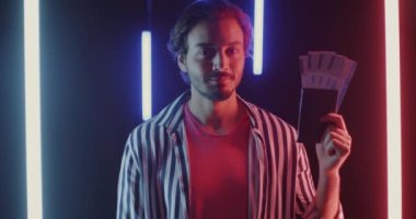 Neşeli Orta Doğulu turist portresi uçak biletlerine işaret ediyor. Karanlık arka planda, neon ışıklı el hareketleriyle. Seyahat ve tatil kavramı.