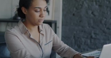 Hırslı bir Afrikalı Amerikalı girişimcinin portresi dizüstü bilgisayarla çalışıyor, daktilo yazıyor, sonra da ofisinde deftere yazıyor. İş ve iş kavramı.