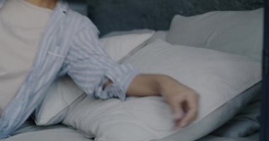 Pijama giyen yorgun genç bir kadının portresi. Yatakta yatıp evde uyuyor. Boş zaman aktivitesi ve rahatlama rutin konsepti.