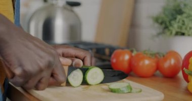 Evdeki mutfak masasında salatalık keserek sağlıklı yemek pişiren erkek eli. Beslenme ve ev yapımı vejetaryen öğle yemeği konsepti.