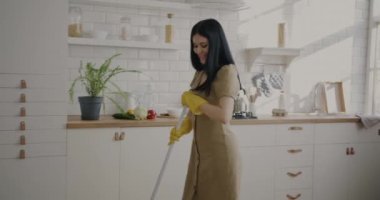 Neşeli ev kadınının portresi. Dans ediyor, mutfak zeminini yıkıyor, paspas temizliği yapıyor. Oda servisi ve milenyum konsepti.