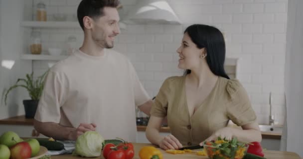 Glada Unga Par Matlagning Grönsakssallad Talar Njuter Dagen Hemma Tillsammans — Stockvideo
