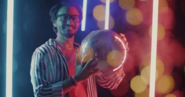 Gece kulübünde neon lambalı disko topuyla dans eden neşeli Orta Doğulu adamın yavaş çekim portresi. Eğlence ve parti konsepti.