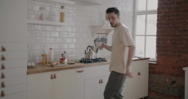 Kulaklık takan, dans eden, çay içen ve evde eğlenen neşeli insan portresi. Modern gençlik kültürü ve yaşam tarzı kavramı.