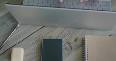 Akıllı telefon, defter ve dizüstü bilgisayarı olan ahşap bir masa. Kadın eli kapalı yerlerde daktilo kullanıyor. İş ve araç gereç kavramı.