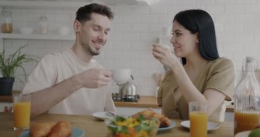 Karı koca sabah kahvaltıda kahve içip mutfakta sırıtarak konuşuyorlar. Aile rutini ve beslenme konsepti.