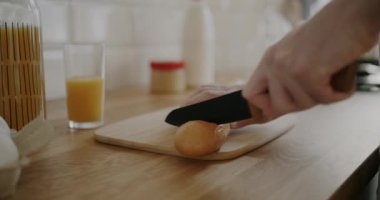 Erkek eliyle ekmeği bıçakla keserken ve evde tek başına yemek yaparken tahta keserken. İnsanlar ve yemek konsepti.