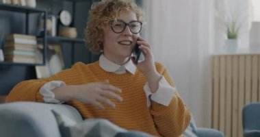 Rahat bir evde cep telefonuyla konuşan neşeli kız arkadaşça sohbetin tadını çıkarıyor. Cep telefonu iletişimi ve modern teknoloji kavramı.