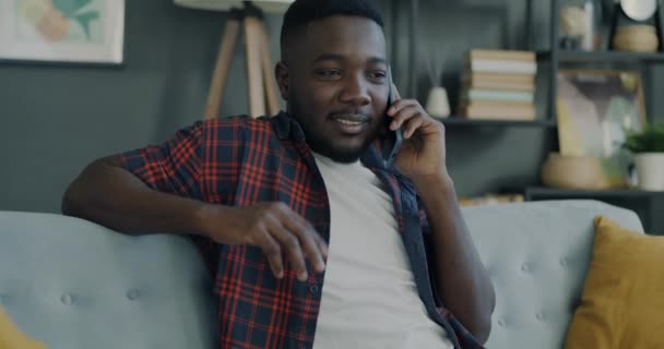 Onbezorgde Jongeman Spreekt Mobiele Telefoon Glimlachend Binnen Een Modern Appartement — Stockvideo