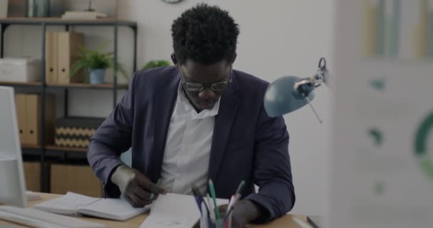 アフリカ系アメリカ人実業家の肖像書類の読み書きを机の上で作業している 人と書類の概念 — ストック動画