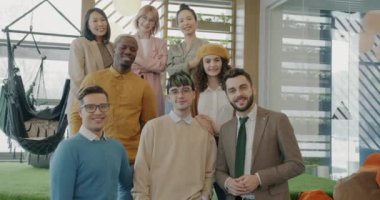 Yaratıcı iş adamları modern bir iş yerinde gülümsüyor ve birlikte kameraya bakıyorlar. İşbirliği ve çağdaş iç konsept.