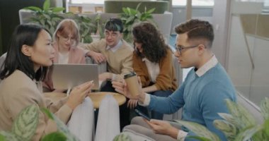 Genç iş adamlarından oluşan bir grup bilgisayarla yaratıcı ofiste iş konuşuyor ve tartışıyorlar. İletişim ve birlikte çalışma kavramı.