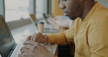 Bilgisayarlı daktilo kullanan hırslı Afro-Amerikan çalışanların yakın çekimleri ortak ofisteki iş arkadaşlarıyla masada oturuyor. İş ve modern teknoloji kavramı.