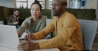 Erkek ve kadın meslektaşlar modern açık uzay ofisinde iş ve dizüstü bilgisayar tartışmaları yapıyorlar. İş iletişimi ve insan kavramı.