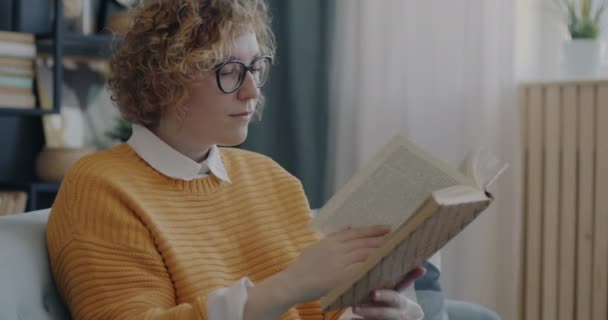 Evdeki Kanepede Oturmuş Ilginç Bir Kitap Okuyan Neşeli Genç Bayan — Stok video
