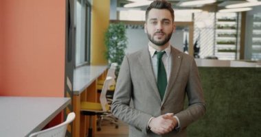 Yaratıcı çalışma alanında durup kameraya bakan yakışıklı genç iş adamının yavaş çekim portresi. Halk ve iş kavramı.