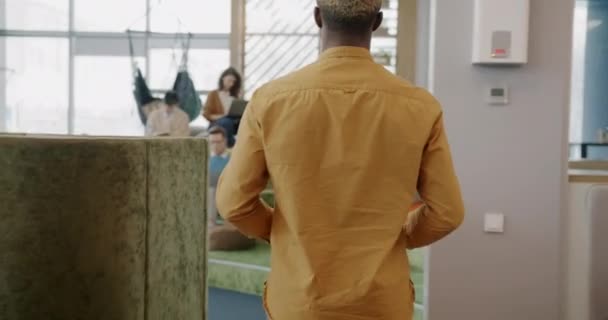 アフリカ系アメリカ人従業員のドリーショットは ラップトップを使用して一緒に話している現代的な創造的な同僚の挨拶を入力してください — ストック動画