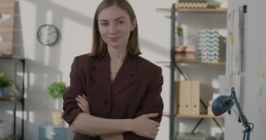 Ofiste tek başına kameraya bakıp gülümseyen kendine güvenen genç bir iş adamı. İş kadını şık kıyafetler giyiyor..