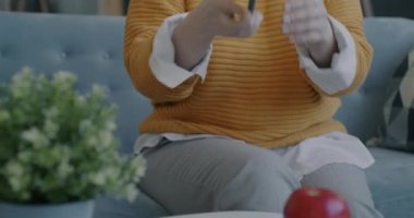 Akıllı telefonu alıp ekranda gülümseyen mutlu genç bir kadın evde internet iletişiminin keyfini çıkarıyor. İnsanlar ve modern teknoloji kavramı.