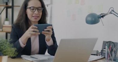 Mobil video oyunu oynayan genç bir bayanın portresi. İş molasında telefon dinlendirici. Modern teknoloji ve eğlence konsepti.