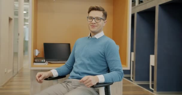 パソコンのデスクに座ってカメラを見て微笑む明るい男性社員の姿 ビジネスマンと職場のコンセプト — ストック動画