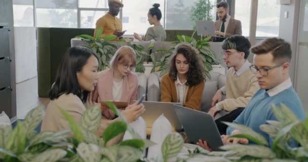 ビジネス関係者のグループがアイデアを話し合い 創造的な共有オフィスでラップトップを使用しています 協力と近代的な技術コンセプト — ストック動画