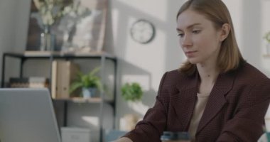 İş yerinde kahve içmek ve daktilo etmek için dizüstü bilgisayar kullanan kadın bir ofis çalışanı. İçeceği ve gençlik yaşam tarzını çıkar..