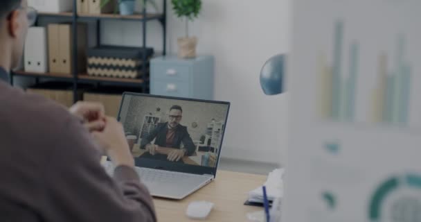 两名男性同事一边打电话一边挥手 一边与办公室的笔记本电脑进行视频通话 讨论商业与合作的伙伴 — 图库视频影像