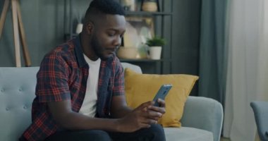 Evdeki akıllı telefonu kullanarak görüntülü konuşma yapmaktan hoşlanan mutlu genç adam. Modern teknoloji ve gençlik yaşam tarzı kavramı.