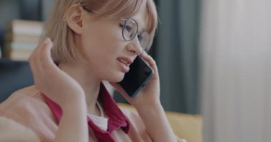 Kaygısız kız öğrenci cep telefonuyla konuşuyor ve evde gülüyor. Cep telefonu iletişimi ve gençlik yaşam tarzı kavramı.