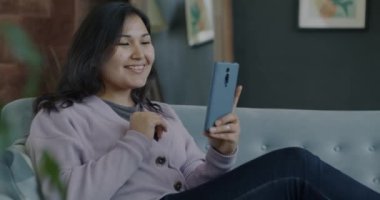 Neşeli öğrenci portresi, evdeki akıllı telefondan güzel jestler yapıyor. İnternet ve iletişim konsepti.