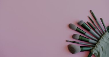 Güzellik ürünleri göz farı paleti, makyaj fırçası seti ve pembe arka planda kadın eli. Moda ve tarz kavramı.