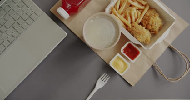 職場で食事をしているビジネスマンながら オフィスのノートパソコンとテーブルの上に配達食品とコンテナを置く手のクローズアップ 製品や仕事の概念を奪う — ストック動画