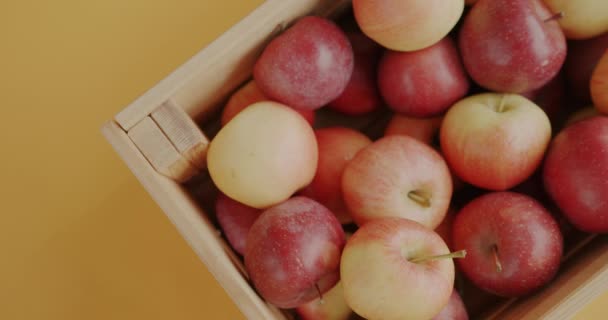 Zbliżenie Żeńskiej Dłoni Wkładającej Świeże Jabłka Drewnianego Pudełka Żółtym Tle — Wideo stockowe