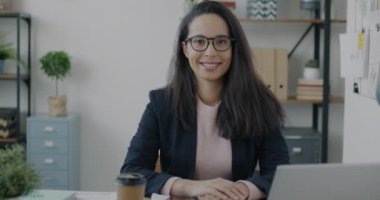 Modern ofisteki kapalı mekanlarda gülümseyen ve kameraya bakan zarif takım elbiseli başarılı Orta Doğulu kadın portresi. Mesleki meslek ve iş dünyası kavramı.