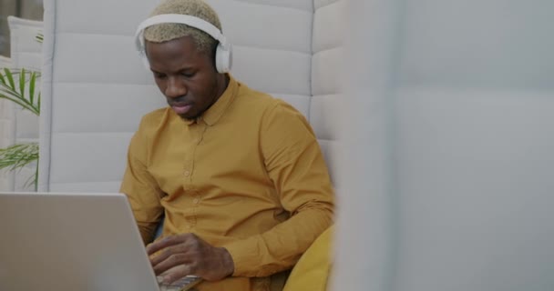 Przystojny Afro Amerykański Przedsiębiorca Współpracuje Laptopem Słucha Muzyki Przez Słuchawki — Wideo stockowe