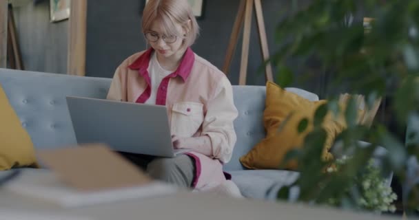 Retrato Jovem Sorridente Usando Laptop Digitando Sentado Sofá Apartamento Sozinho — Vídeo de Stock