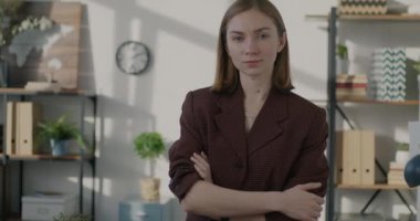 Kollarını kavuşturup kameraya bakan başarılı genç iş kadınının yavaş çekim portresi. Halk ve meslek kavramı.