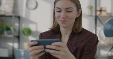 Akıllı telefonlu video oyunu oynayan genç ve mutlu bir ofis çalışanı. Tatilin tadını çıkarıyor. Eğlence ve modern teknoloji konsepti.