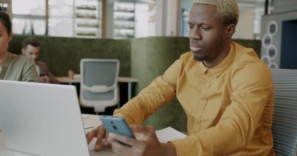 Hombre Afroamericano Está Escribiendo Con Ordenador Portátil Uso Teléfonos Inteligentes — Vídeos de Stock
