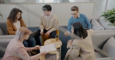 Motive olmuş çalışanlar, iş geliştirme konusunda fikir alışverişinde bulunarak rahat bir ofis odasında çalışıyorlar. Gençlik ve meslek kavramı.