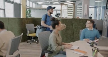 Üniformalı kurye, modern ofisteki bir grup iş adamına yiyecek ve içecek getiriyor. Yemek molası ve yaşam tarzı konsepti.