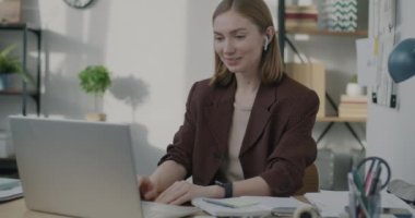 Genç iş kadını internette iş birliğini tartışırken bilgisayarını ve kulaklığını kullanıyor. İletişim ve iş konsepti.