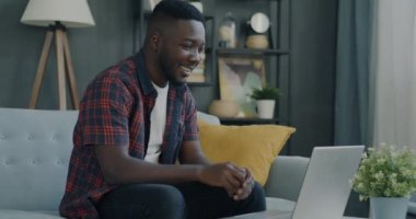 İnternette sohbet eden neşeli öğrenci dairede dizüstü bilgisayar kullanarak el sallıyor. Uzak iletişim ve elektronik aygıt kavramı.