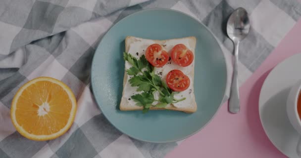 ピンクのテーブルにお茶のプレートカップとオレンジの半分においしいランチサンドイッチのズームアウト 栄養と健康的なライフスタイルのコンセプト — ストック動画