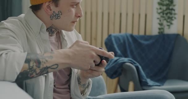 兴奋的家伙千年玩电子游戏在家里表达快乐的活动 有穿刺和纹身的年轻人独自玩乐 — 图库视频影像