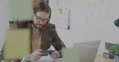 Ofiste akıllı telefonuyla video oyunu oynayan yaratıcı iş adamının portresi. Modern teknoloji ve iş arası kavramı.